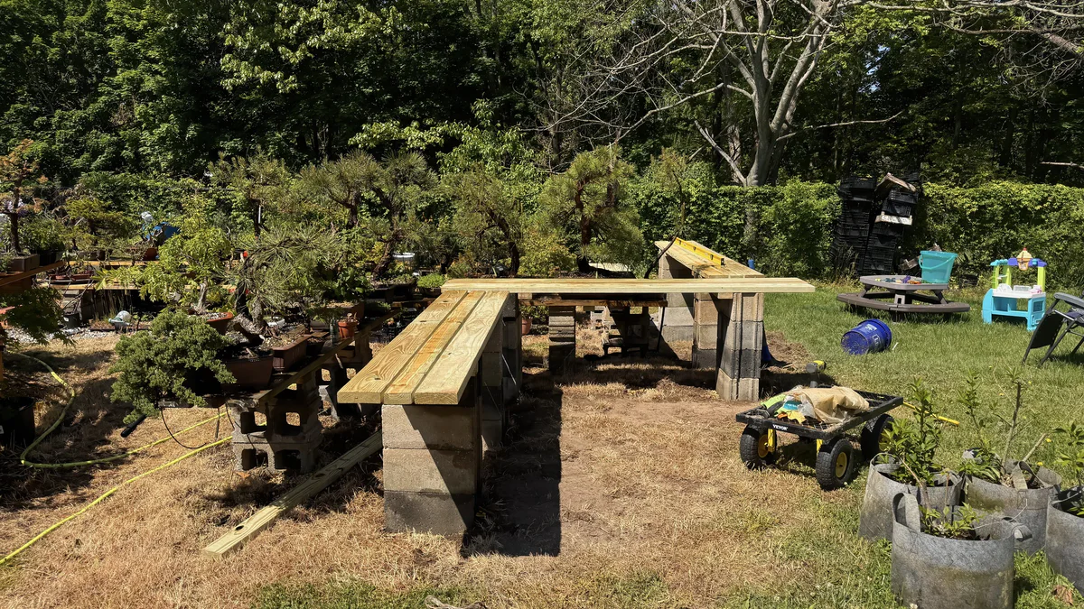 New lumber benches on cinder blocks, half built, with tools and a garden cart nearby