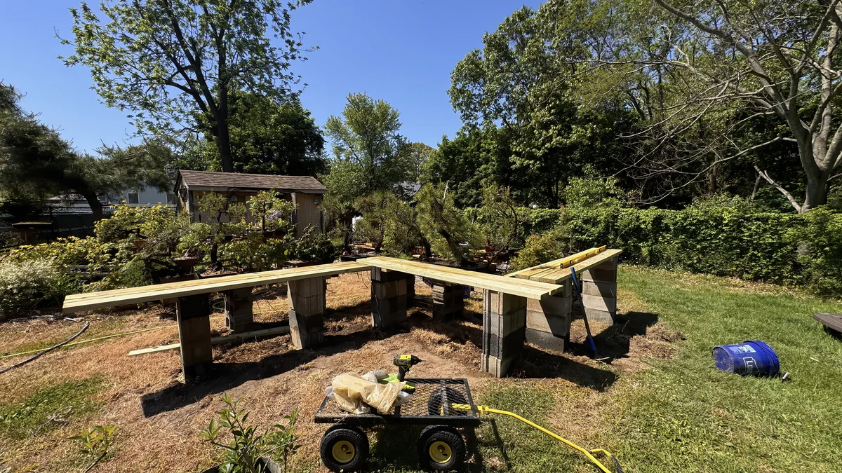 A long run of new lumber benches on cinder blocks, still empty